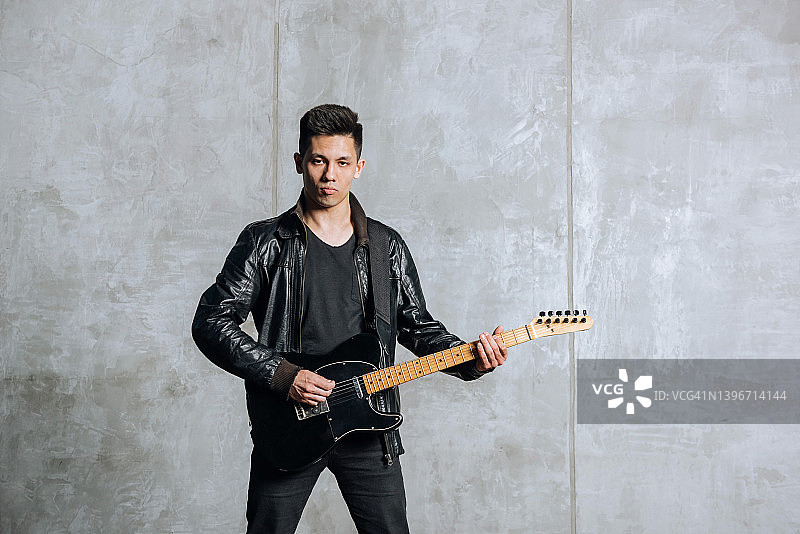 严肃的摇滚音乐家抱着吉他看着镜头演奏音乐图片素材