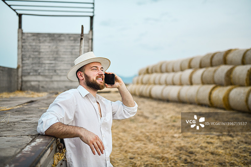 微笑的络腮胡农民安排买家购买田野上的干草堆图片素材