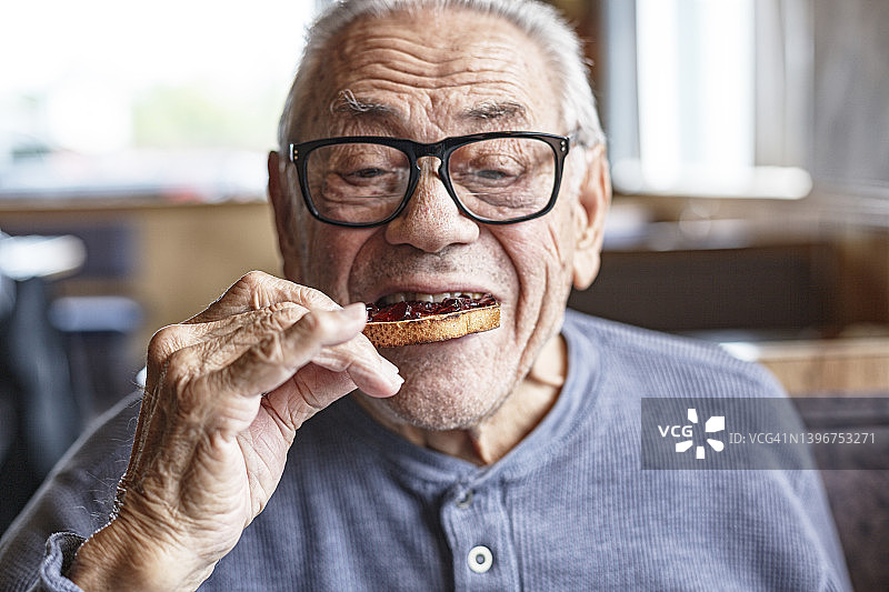 年长男人早餐吃果酱烤面包图片素材