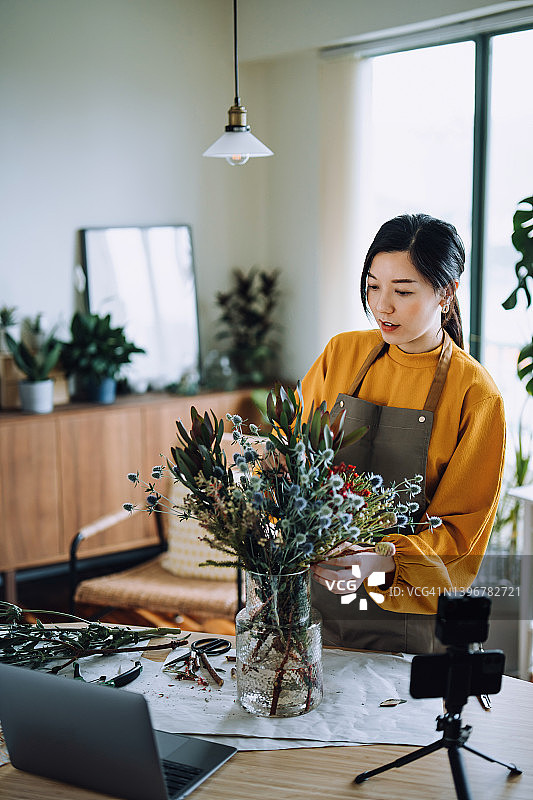 年轻的亚洲女花艺师在家用笔记本电脑和相机录制花束插花课程图片素材