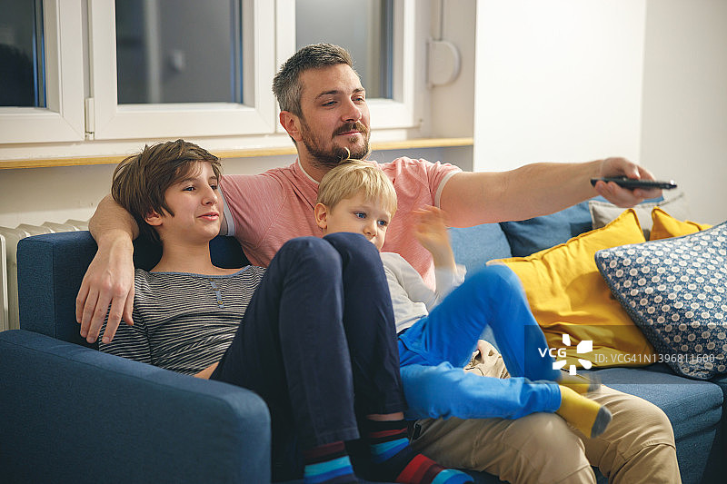 父亲节，快乐的父亲和两个儿子在家看电影图片素材