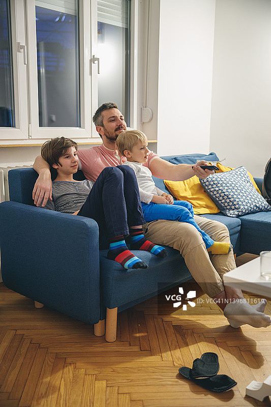 父亲节，父亲舒适地坐在沙发上与儿子们在一起图片素材