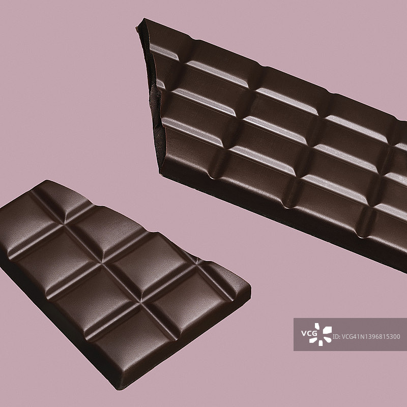 粉色背景上的碎巧克力棒特写。图片素材