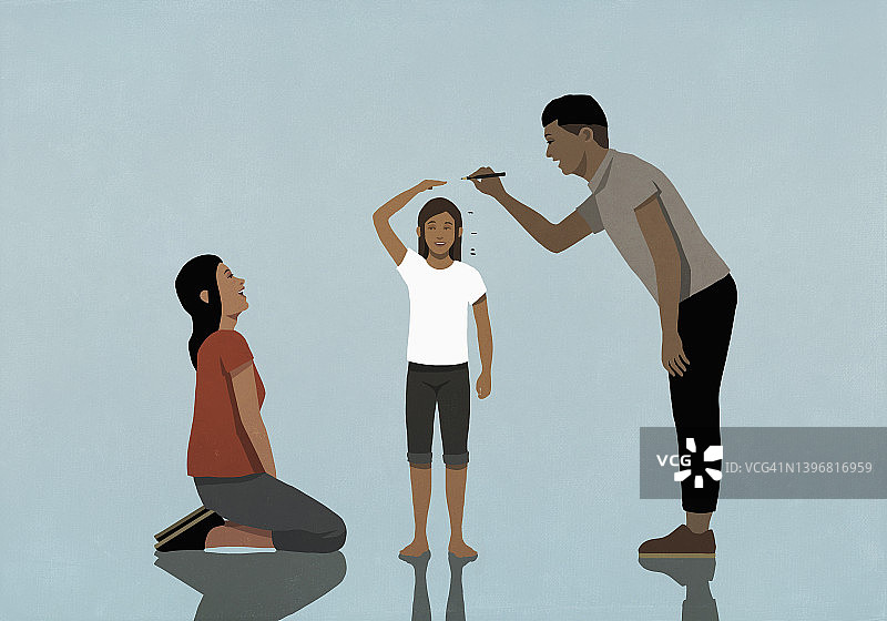 幸福的父母测量并标记女儿的身高图片素材