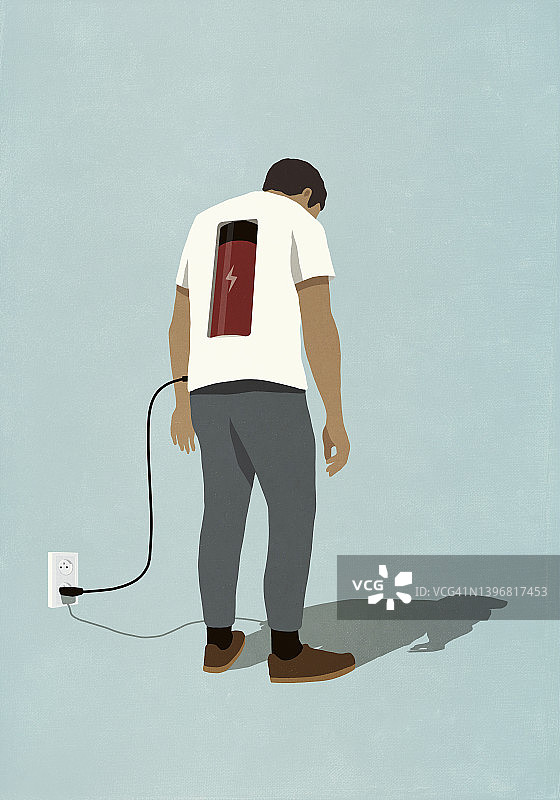 男子用插头在背后给电池充电，站在电源插座旁图片素材