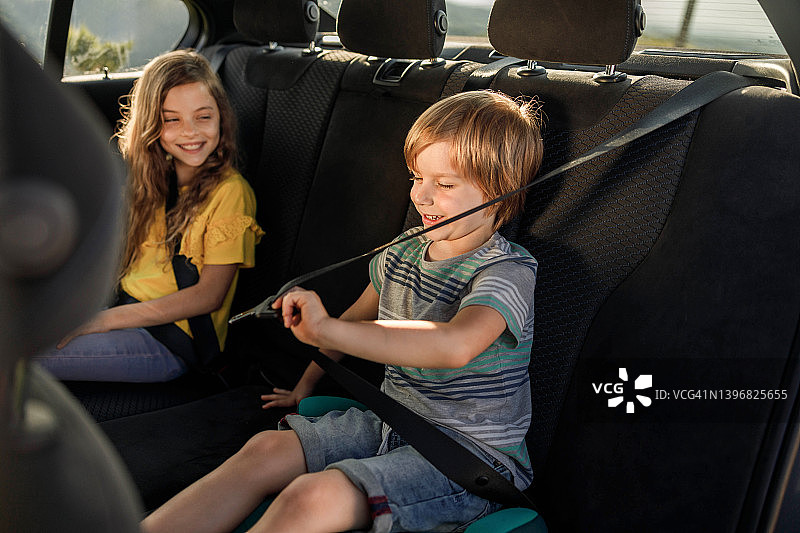 快乐的小男孩在汽车后座上系安全带图片素材