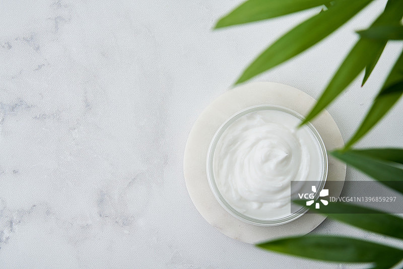 大理石桌上已开封的白色美容保湿霜产品，高角度视图，复制空间图片素材
