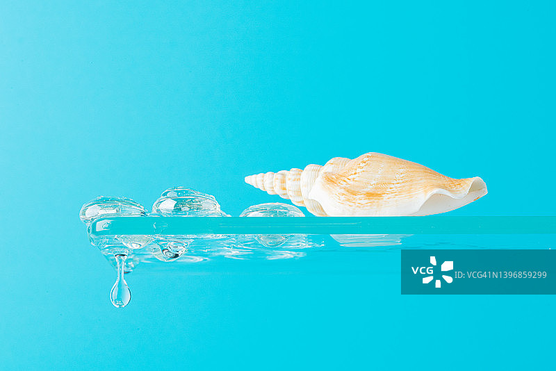水下场景：贝壳在玻璃架上，蓝色背景上的水花和水滴图片素材