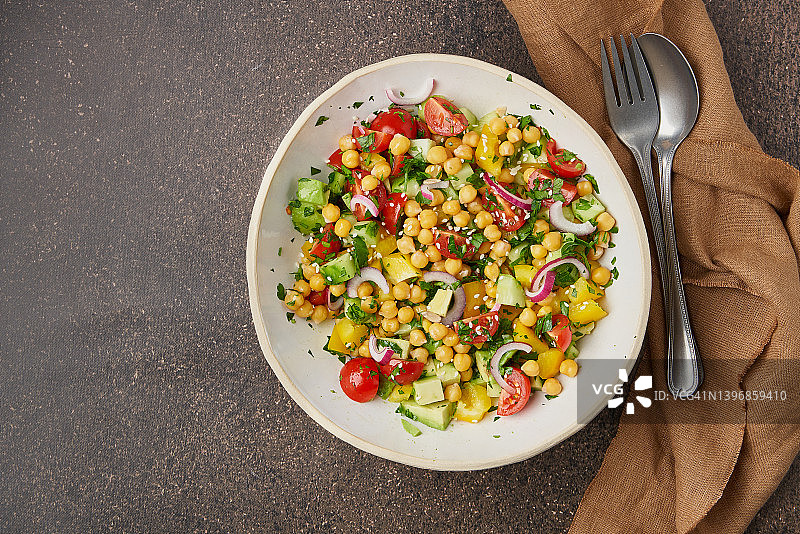 美味的素食地中海沙拉，含甜玉米、番茄片、鲜黄瓜、红洋葱碎、欧芹，搭配健康饮食图片素材