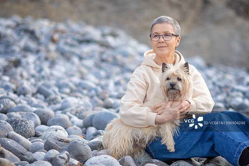 女人在海滩上和狗一起休息图片素材