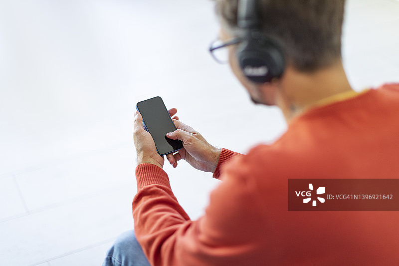 年轻男人在家用智能手机放松听音乐图片素材