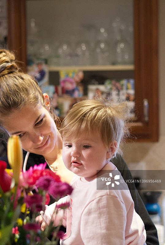 年轻的母亲和带着鲜花的婴儿图片素材