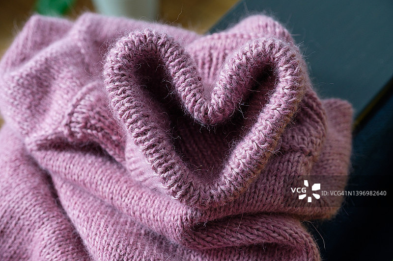 针织毛衣和金属针织针。衣服做成的心。爱的宣言。粉色羊毛纱线。爱好、创意、针线活和手工的概念。情人节。用自己的双手制作衣服。图片素材