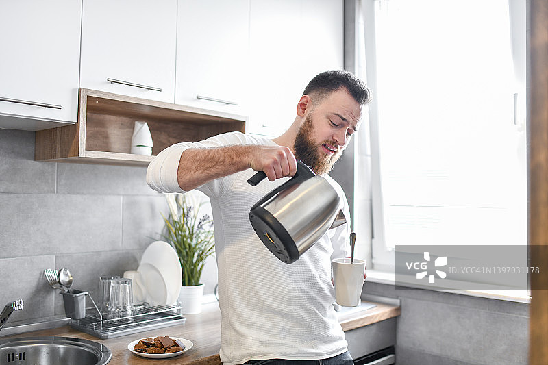 在厨房倒咖啡的英俊男人图片素材