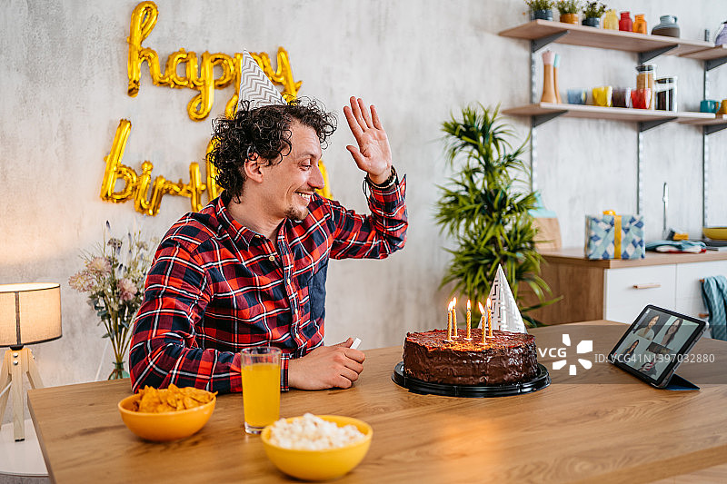 在生日聚会上用平板电脑与朋友交谈的年轻人图片素材