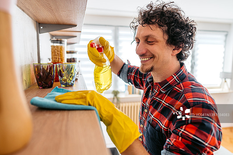 年轻男人清洁客厅置物架图片素材