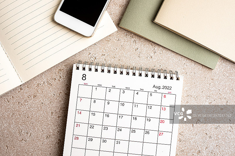 办公桌及文具，笔记本电脑、记事本、智能手机、2022年8月日历，混凝土背景，俯视图，可复制图片素材