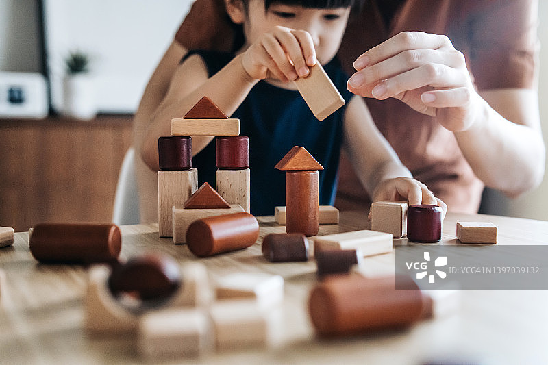 年轻的亚洲母亲和女儿一起玩积木，享受亲子时光图片素材