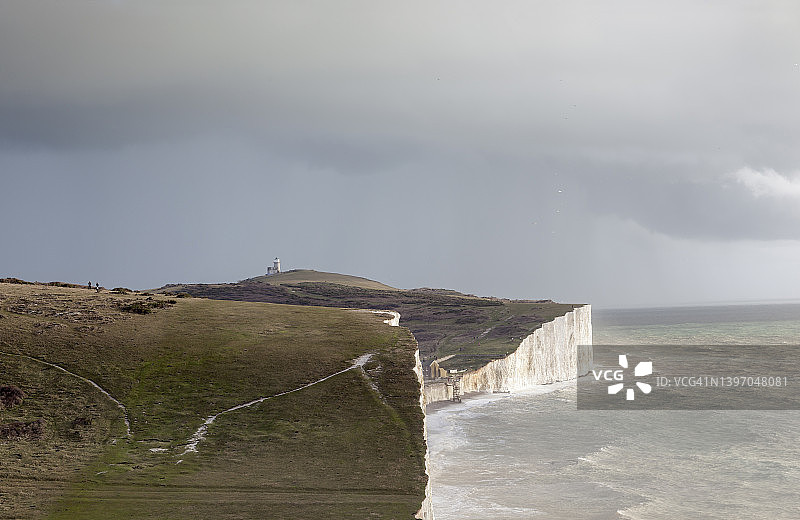 秋日海边，人们沿着白色悬崖走向灯塔图片素材
