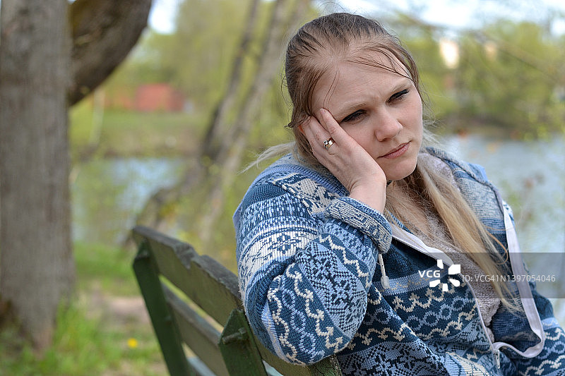 年轻女子坐在湖边长椅上的肖像图片素材
