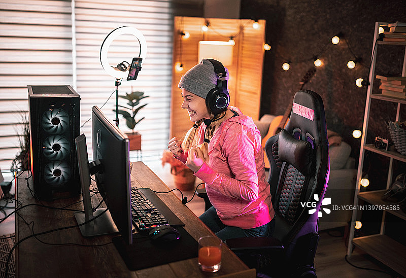 女孩在家玩电子游戏并直播。图片素材