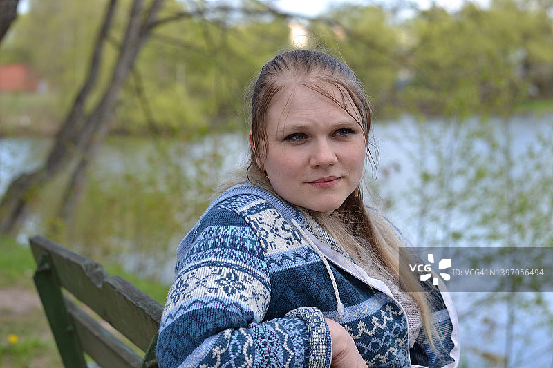 年轻女子坐在湖边长椅上的肖像图片素材