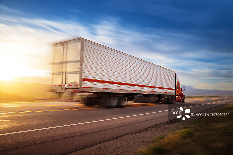 日出时分美国单车道上飞驰的红白色16轮货车图片素材