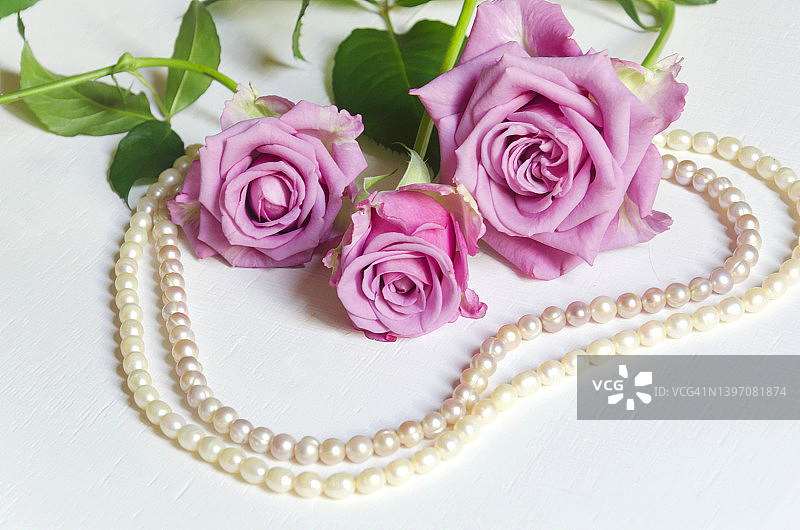 白色背景上的粉色玫瑰与珍珠项链图片素材