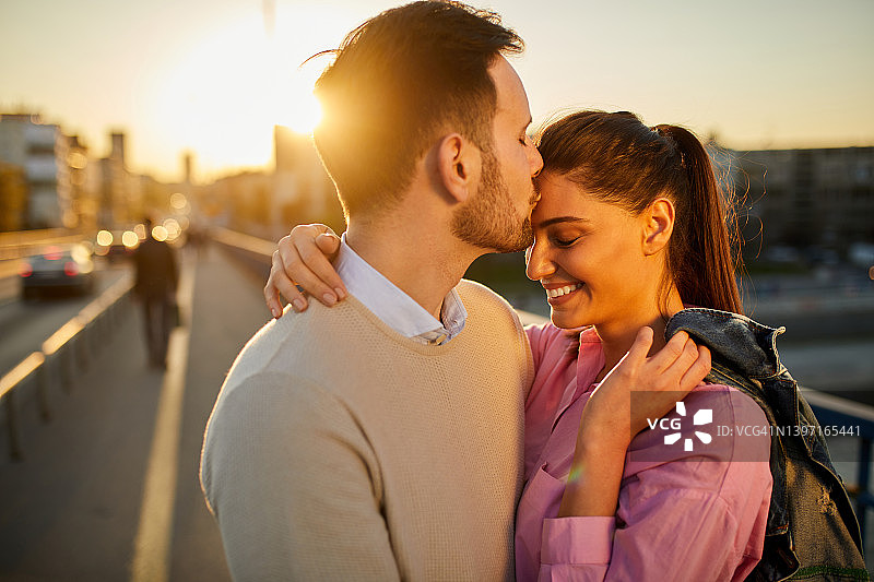 相爱中的年轻情侣在桥上拥抱亲吻图片素材