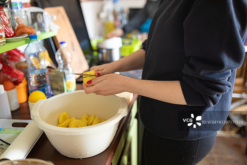 女子在家庭厨房切土豆（未识别面部）图片素材