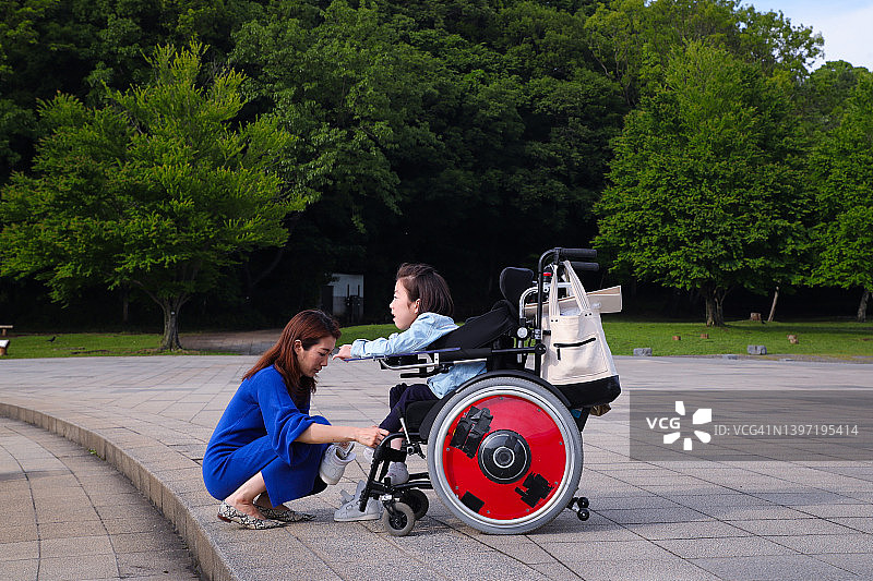 坐在轮椅上享受户外的亚裔女孩图片素材