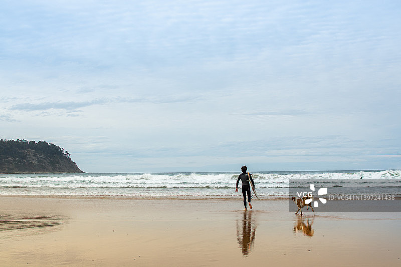 带着狗走向大海的冲浪者图片素材