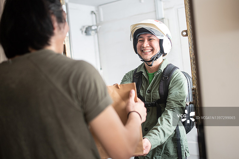 中国外卖员戴着摩托车头盔送餐到住宅图片素材