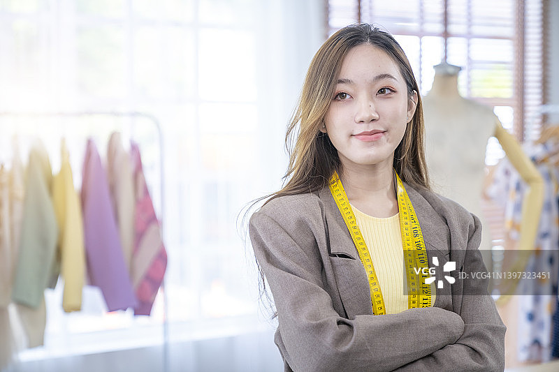 微笑的年轻亚洲时装设计师站立并交叉双臂于工作室图片素材