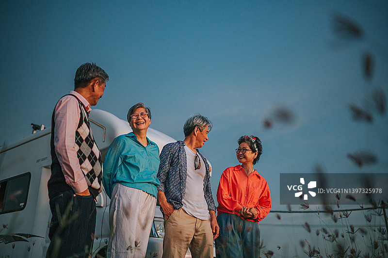 低角度视角：中国亚洲活跃老年人欣赏露营车前稻田的美景图片素材