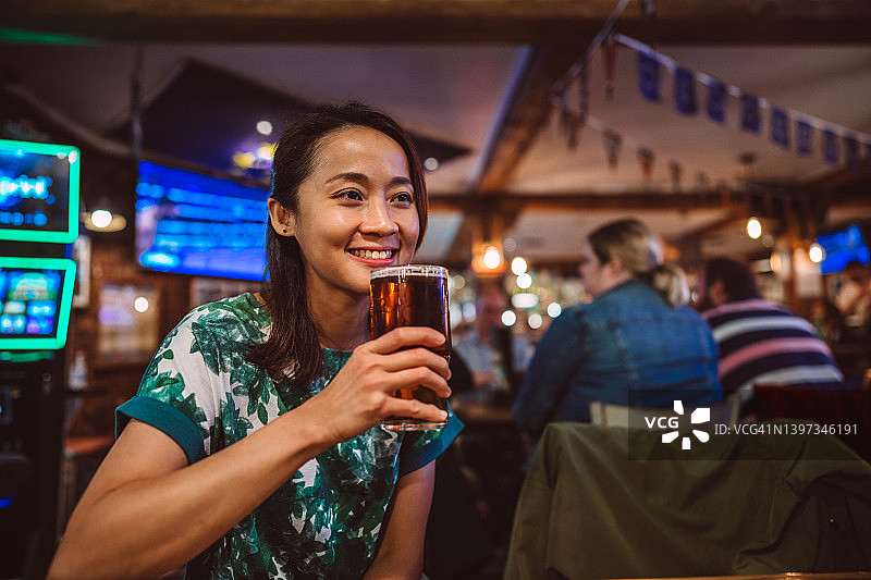 年轻漂亮的亚洲女性在酒吧里享受啤酒图片素材