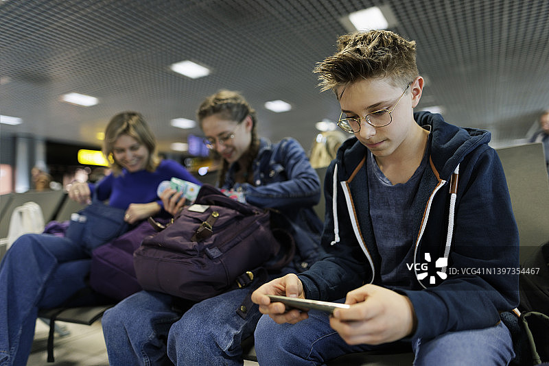 母亲和青少年在机场等候图片素材