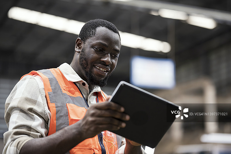 制造过程中集中的机器性能：男性生产工程师使用平板电脑监控机器故障，并通过生产线车间的实时分析将利用率分配给其他机器。图片素材