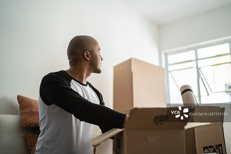 年轻男人搬家，打包搬家纸箱时若有所思图片素材