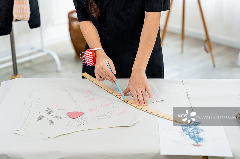 亚洲青年时装设计师在工作室的桌子上绘制服装设计草图图片素材