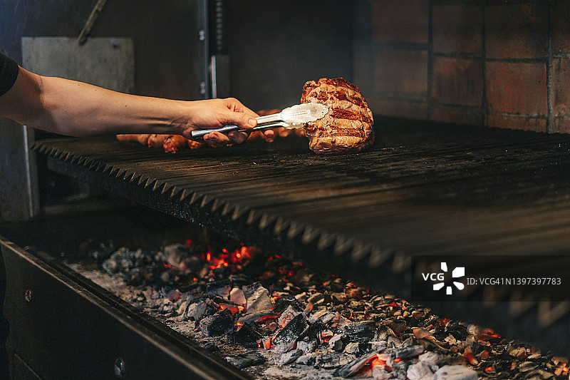 厨师将肉放在烤架上的特写图片素材