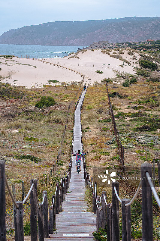 男人沿着木板路走向金乔海滩的后视图图片素材