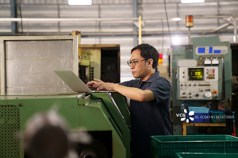 技术员用笔记本电脑检查数控机床的运行图片素材