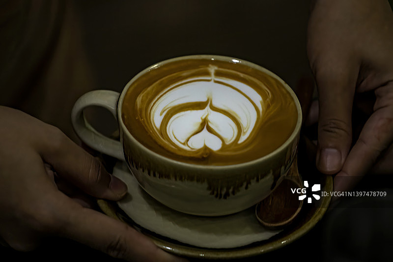 女人手捧一杯热拿铁咖啡图片素材