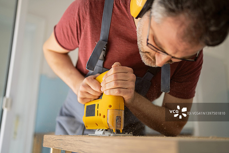 制作家具时，白人男木匠使用曲线锯切割厨房台面图片素材