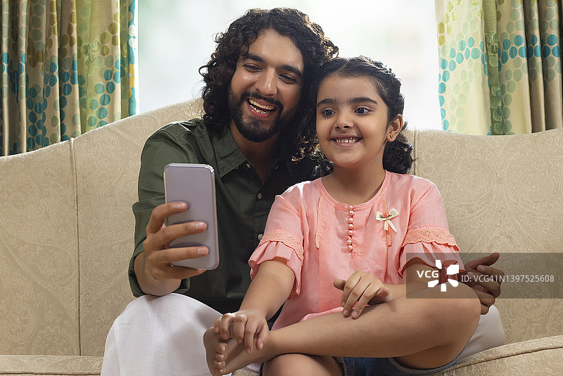 父亲在家中沙发上与女儿自拍图片素材