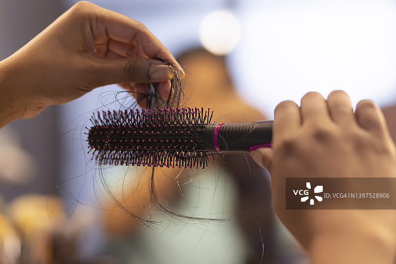 特写：女人拿着梳子，上面有掉落的头发图片素材