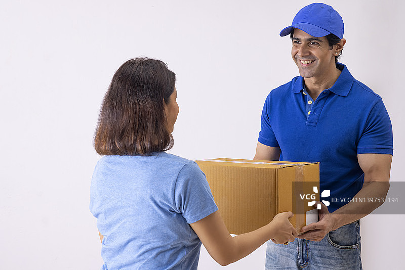 穿着蓝色T恤的送货员给一位女士送包裹图片素材