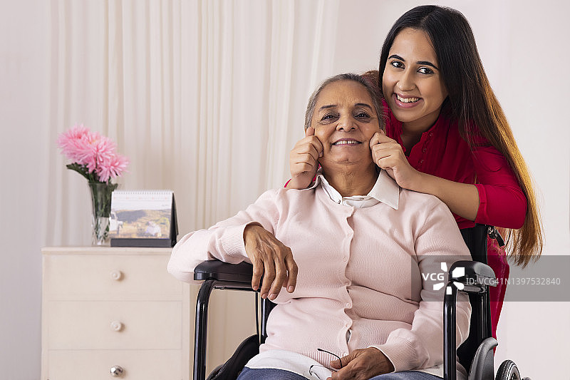 孙女拉着坐在轮椅上的祖母的脸颊图片素材