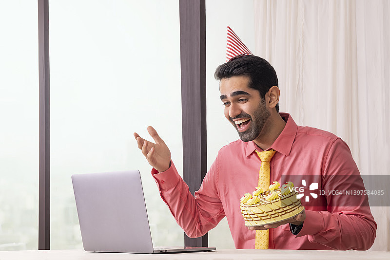 快乐职场男士在办公室通过视频聊天与朋友庆祝生日图片素材